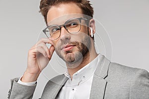 Portrait of serious handsome man in eyeglasses using earphones