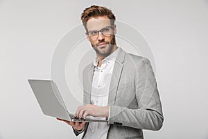 Portrait of serious handsome man holding and using laptop