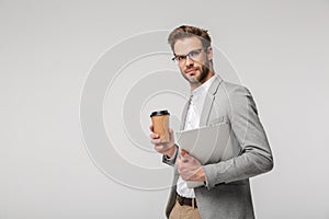 Portrait of serious handsome man posing with laptop and paper cup