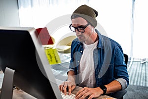 Portrait of serious hipster man working at computer desk