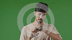 Portrait of serious impatient arabian man guy waiting for meeting over green background looking at clock frustrated