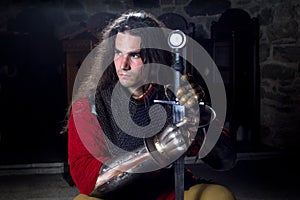 Portrait of Serious Knight in Chain Mail With Metal Gloves and Sword Looking Away