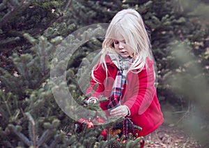 Portrait of serious little girl decorating fir trees