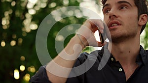 Portrait of serious man having phone conversation outdoors.