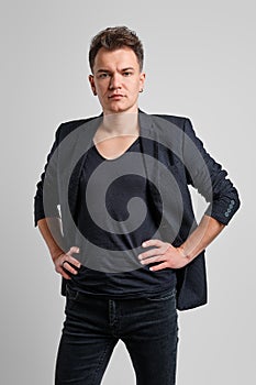 Portrait of serious man in jeans, t-shirt and fitted jacket with hands on waist