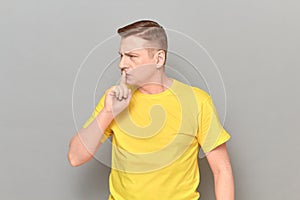 Portrait of serious man putting finger up to lips and saying shh