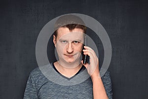 Portrait of serious man speaking on phone and smiling slightly