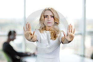 Portrait of serious mature blonde woman making stop sign with both hands.