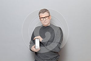 Portrait of serious mature man with glasses holding big book in hands