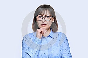 Portrait of serious middle-aged woman on light studio background