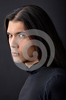 Portrait of serious mysterious fashion man with long dark hair and black eyes, isolated