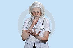 Portrait of serious pensive aged woman doctor with mockup tablet pc.