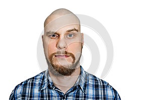 Portrait of a serious, pensive, bald guy with a beard with narrowed eyes looking at the camera on an isolated background