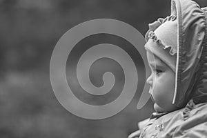 Portrait of a serious pensive eleven month old baby girl on a natural background with copy space, black and white