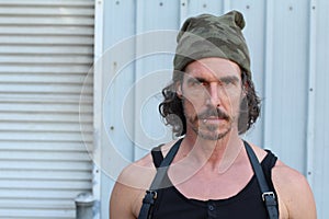 Portrait of a serious pierced man with a beard and a camouflage beanie