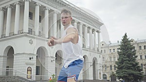 Portrait of serious professional male dancer performing modern dance in city center. Camera zooms out as young confident