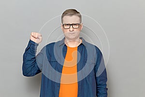 Portrait of serious rebellious mature man raising clenched fist up