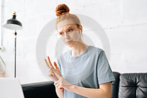 Portrait of serious redhead young businesswoman freelancer counting using fingers during video call
