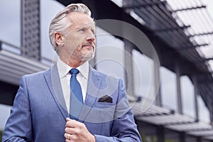 Portrait Of Serious Senior Businessman CEO Chairman Standing Outside Modern Office Building