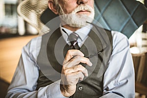 Portrait of serious senior businessman. Focus on hand.