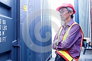 Portrait of serious senior elderly Asian worker engineer wearing safety vest and helmet, standing with arms crossed with blue