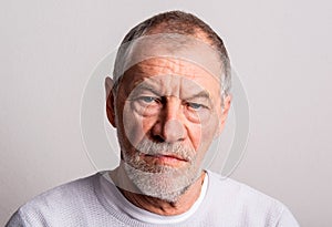 Portrait of a serious senior man in a studio, looking at camera.