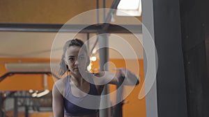 Portrait of serious sportswoman using ropes for crossfit. Beautiful young Caucasian woman exercising in gym. Sport