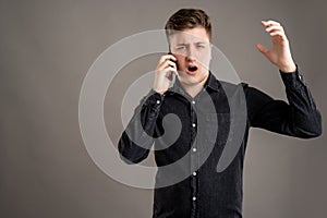 Portrait of serious stylish attractive man dressed with a casual black shirt talking on the phone, gesturing angry face