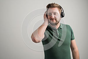 Portrait of serious stylish attractive man with thick beard, dressed in casual green t shirt listen good music