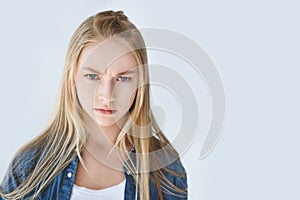 portrait of serious teenage girl with blond hair looking at camera