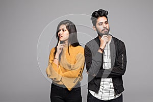 Portrait of serious thinking young loving indian couple isolated over gray background looking aside