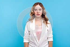 Portrait of serious upset unsmiling beautiful woman looking at camera with sad eyes. blue background