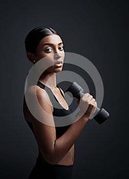 Portrait, serious and woman with dumbbell for exercise in studio isolated on black background. Strong, bodybuilder and
