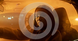 Portrait of serious woman enjoying night drive while sitting in car and looking at the camera