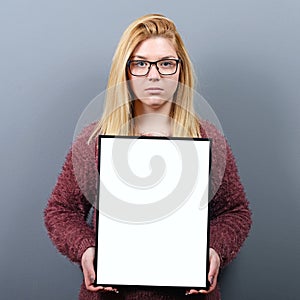 Portrait of serious woman holding blank sign board.Studio portrait of young woman with sign card against gray background