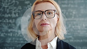 Portrait of serious woman scientist in glasses looking at camera in university class