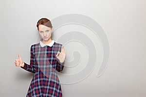 Portrait of serious woman showing okay gesture, giving thumb up sign