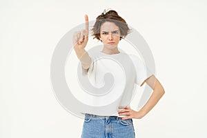 Portrait of serious woman shows one finger, rule or taboo gesture, disapprove something, scolding person, frowning at