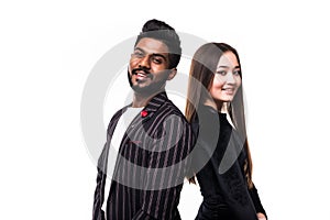 Portrait of a serious young asian couple dressed in formal wear standing back to back over white background