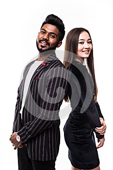 Portrait of a serious young asian couple dressed in formal wear standing back to back over white background