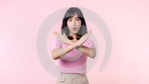 portrait serious young asian woman with cross arm gesture showing stop, no, wrong, denial, rejection sign isolated on pink pastel