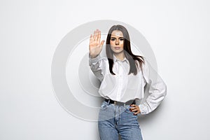 Portrait of a young woman standing with outstretched hand showing stop gesture isolated over white background