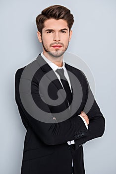 Portrait of serious young businessman in black suit with crosed hands