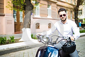 Portrait of serious young businessman on motorbike on city street