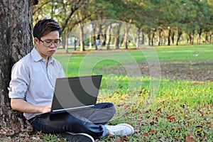 Portrait of a serious young businessman working on his laptop computer in city park with copy space background.