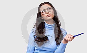 Portrait of serious young businesswoman wearing blue long sleeve blouse and round transparent eyeglasses. European female office