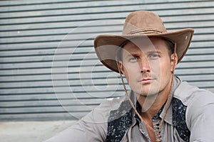 Portrait of serious young cowboy with hat isolated on textured gray background with copy space