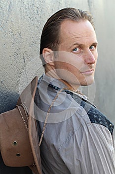 Portrait of serious young cowboy with hat looking away isolated on textured gray background