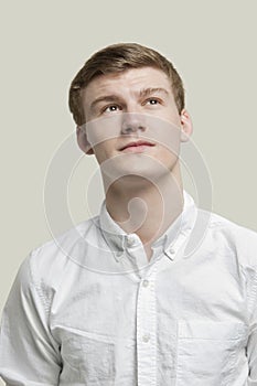 Portrait of serious young man looking up against gray background