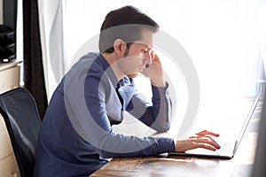 Portrait of serious young man on phone call with laptop
